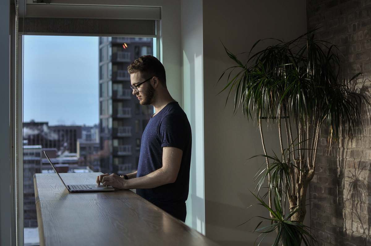 vase man standing beside table using laptop pottery