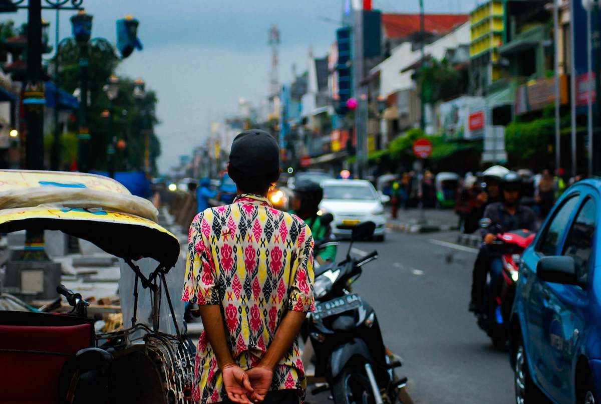 human man standing near black motorcycle with passing vehicles during daytime person