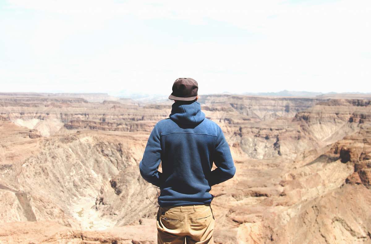 human man standing on mountain cliff under cloudy sky person