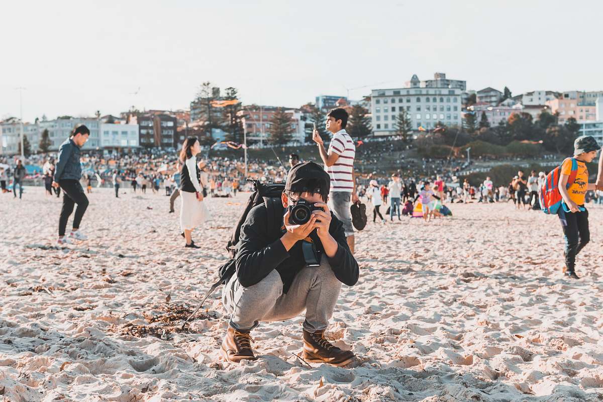 person man taking photo on white sand beach human