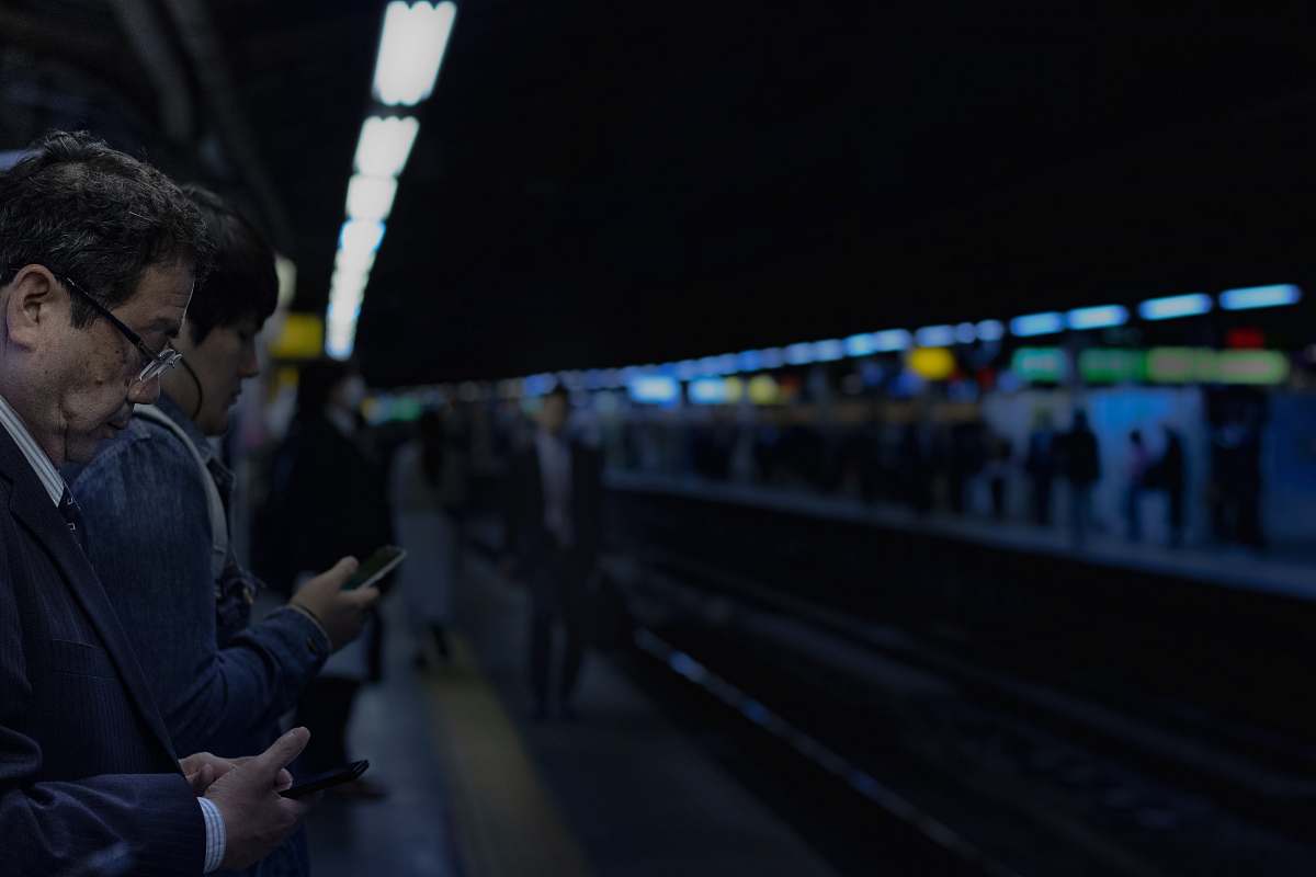 human man waiting for train white holding cellphone person