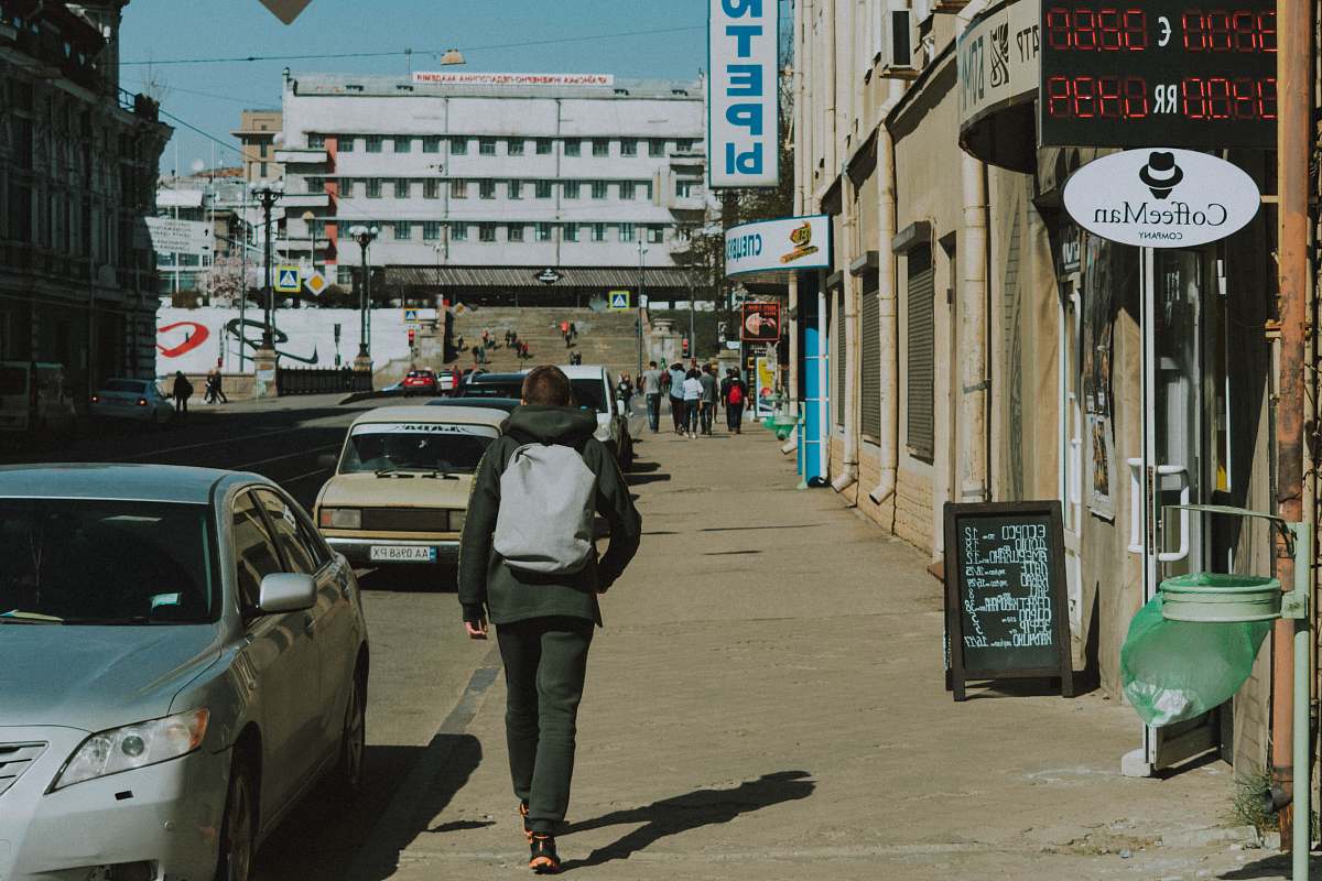 human man walking along sidewalk during daytime person