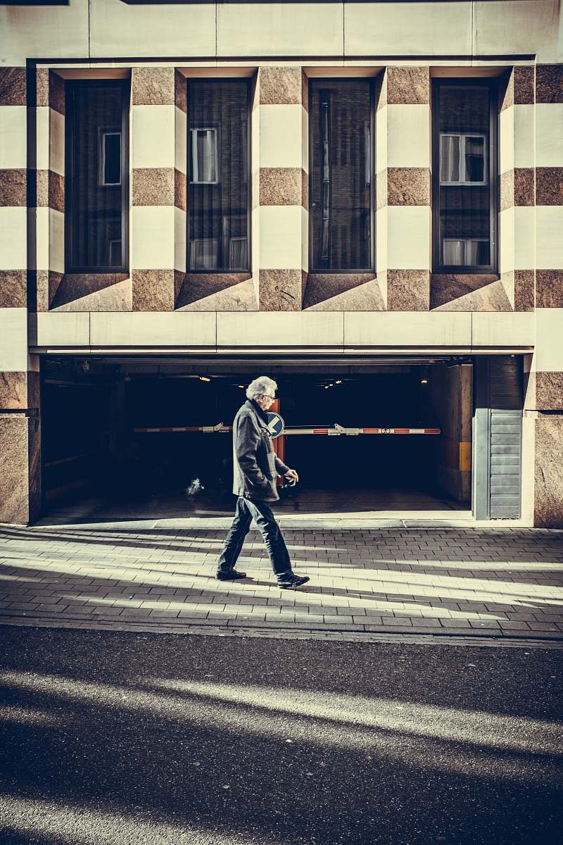 person man walking on pavement in front of concrete structure human