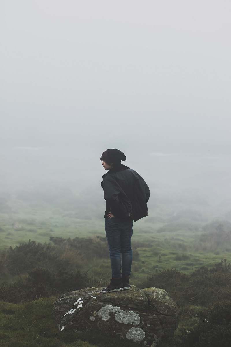 human man wearing black jacket standing on rock person