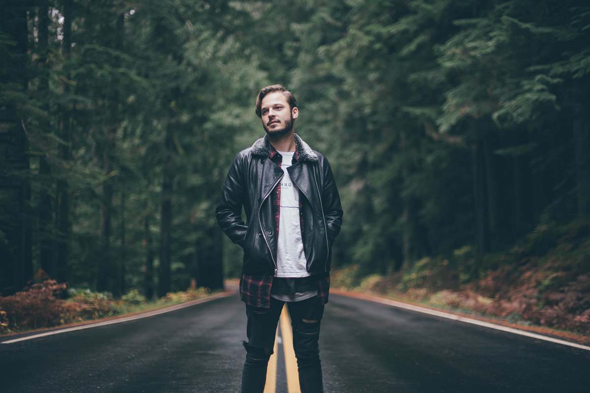 person man wearing black zip-up jacket standing in middle of road jacket
