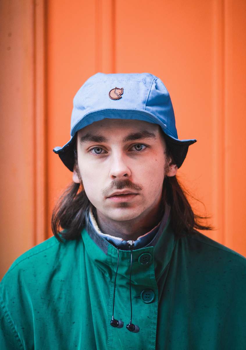 person man wearing blue cap and green jacket looking straight to the camera human