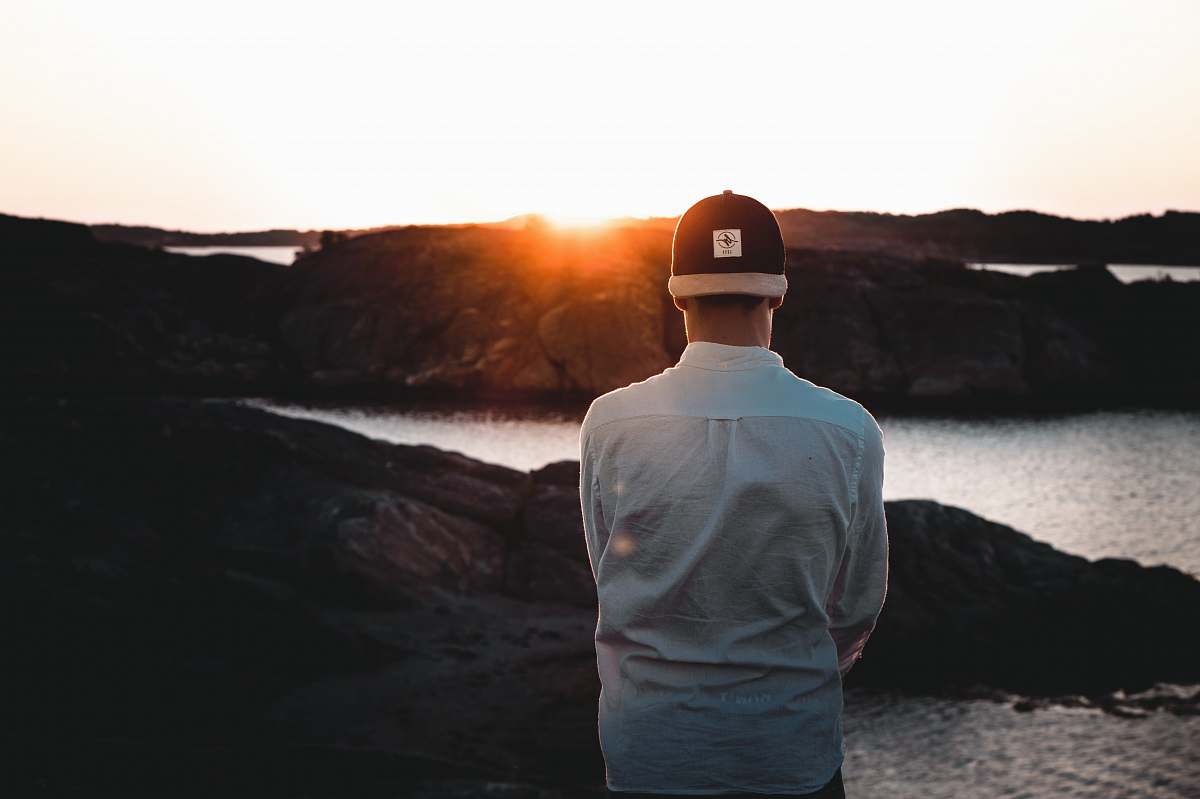 human man wearing cap backwards facing the sea person