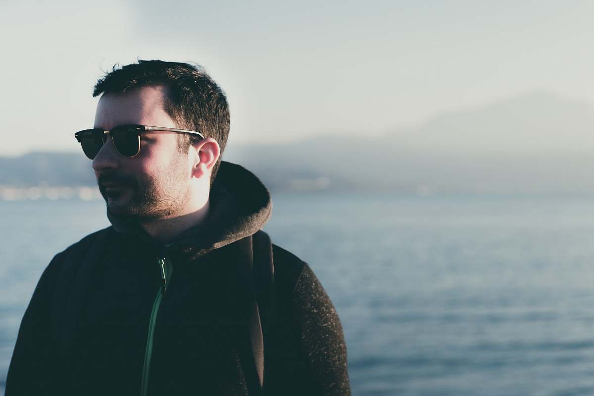 human man wearing eyeglasses standing near body of water person