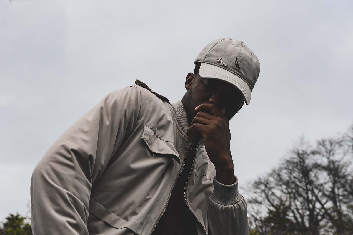 human man wearing gray jacket and cap under the gray clouds person