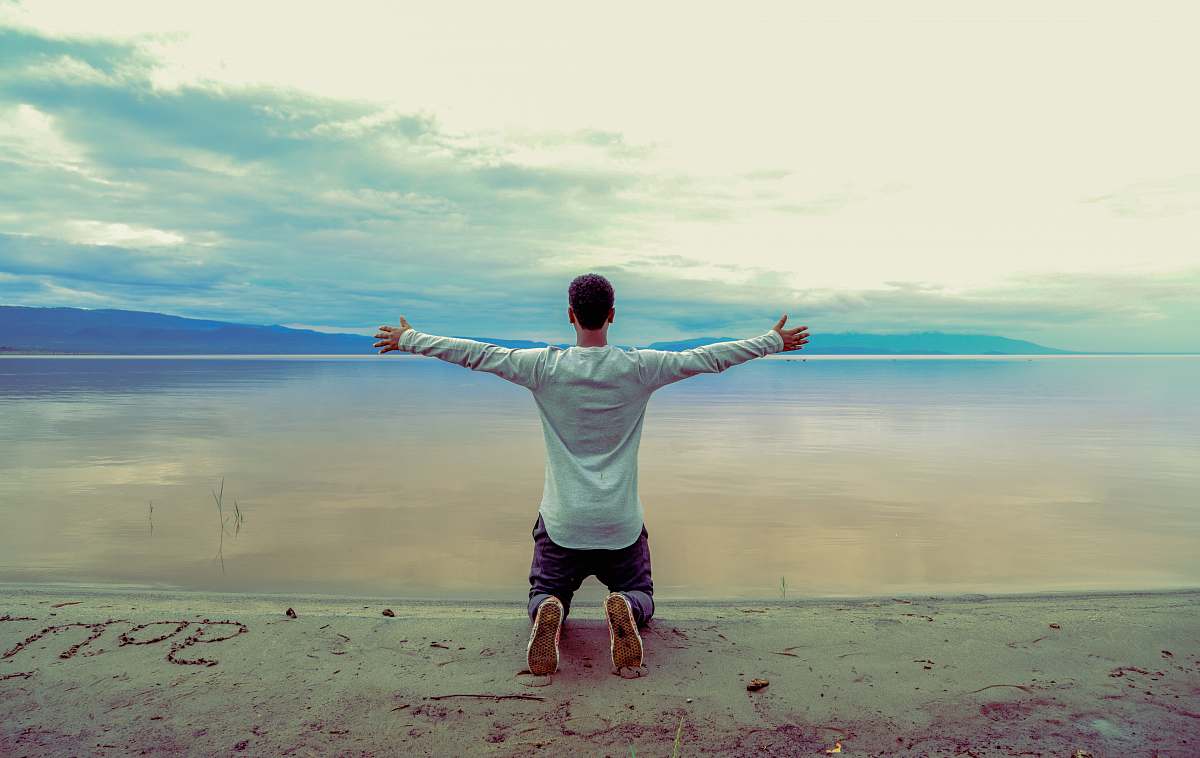 human man wearing gray long-sleeved shirt beside seashore during daytime person