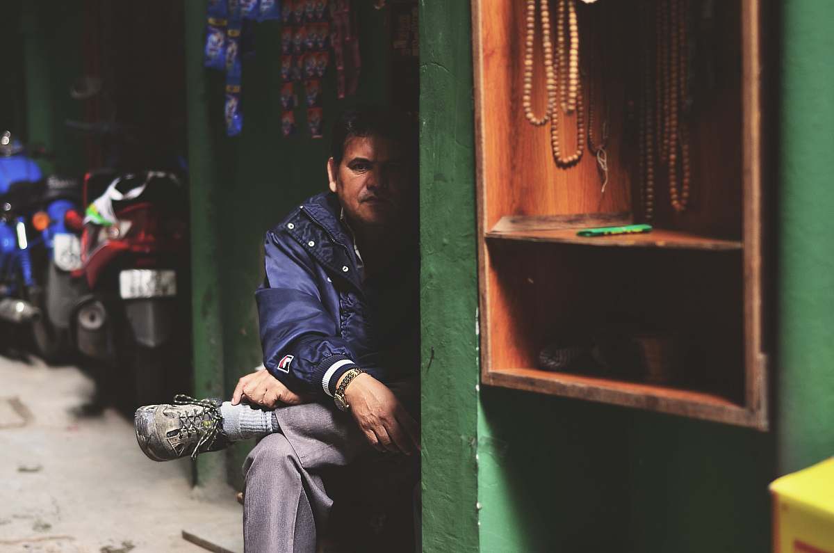 human man wearing purple jacket and gray pants near brown wooden shelf rack during daytime person