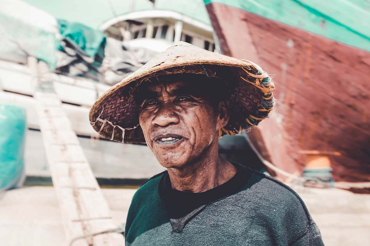 person man wearing straw hat near ships during day human