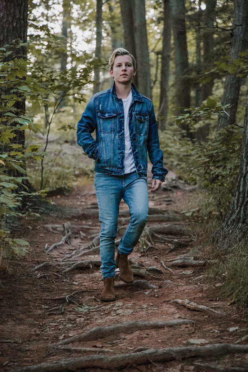 person men's blue denim button-up jacket between trees human