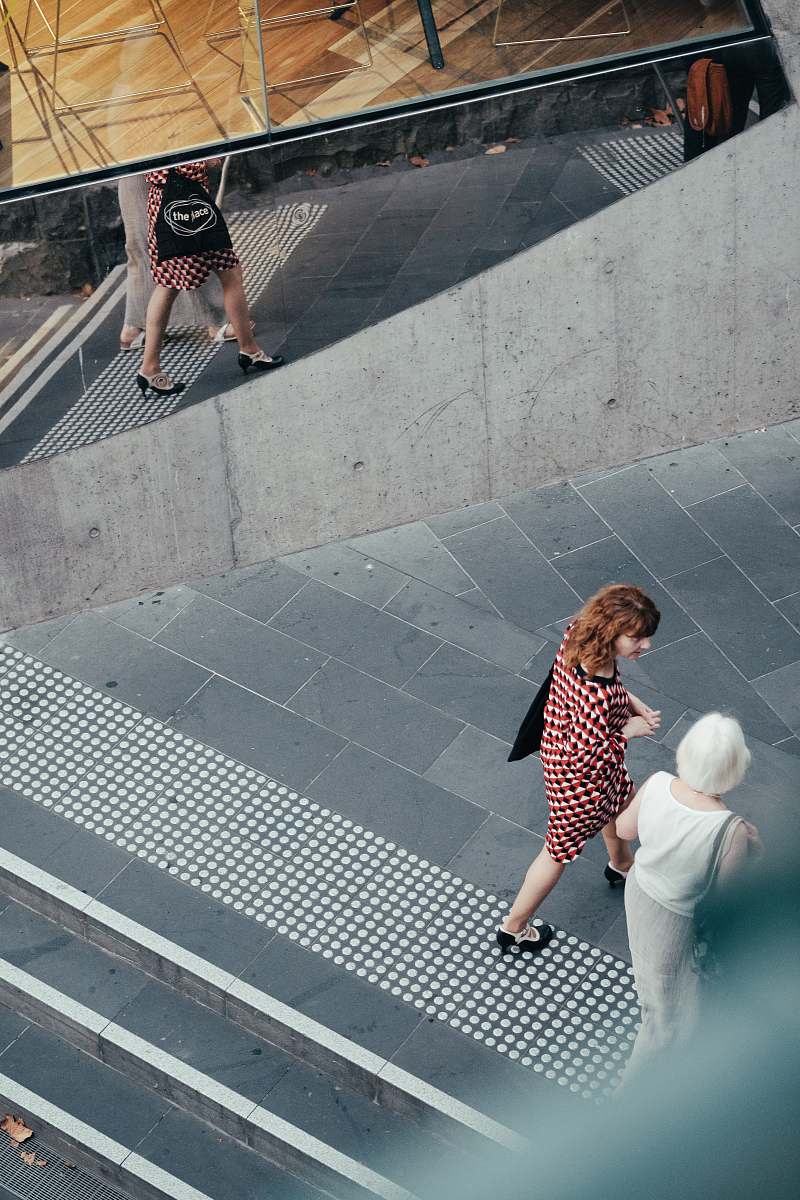 person people walking on street near mirrored wall human