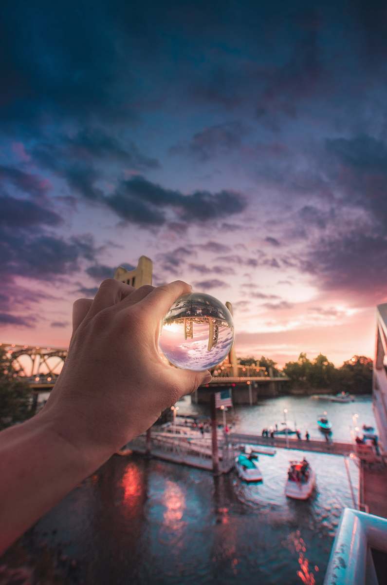 person person holding crystal with reflected boat human