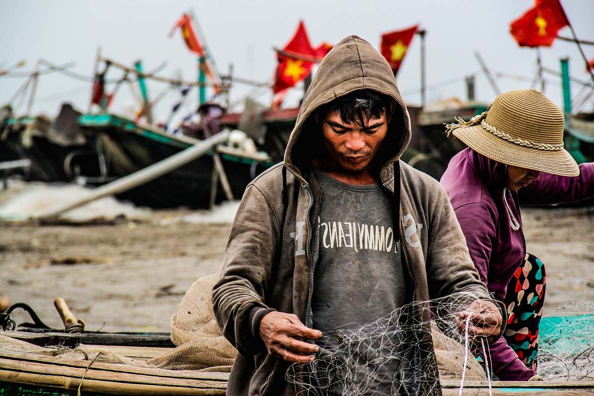 person person holding fishing net near brown boat during daytime human