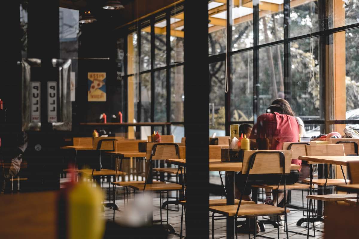 human person sitting on brown wooden chair cafe