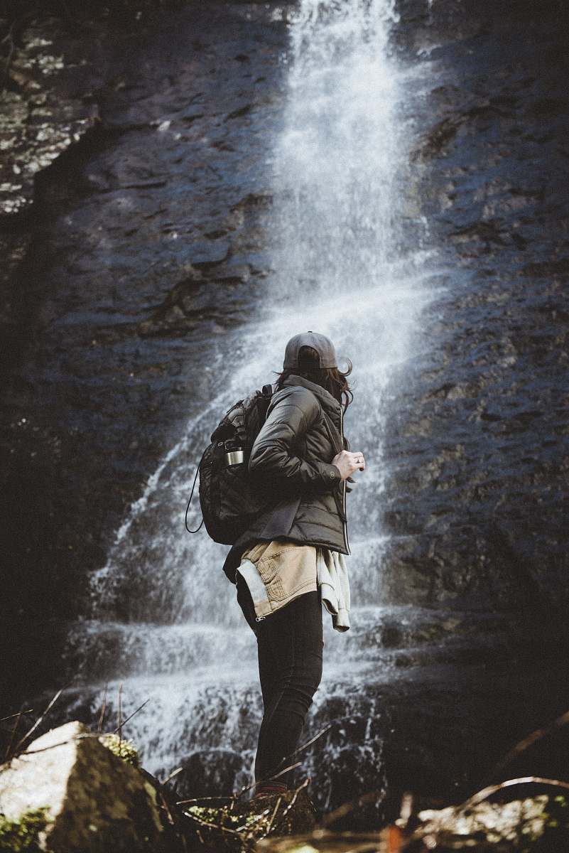 human person standing beside waterfalls person