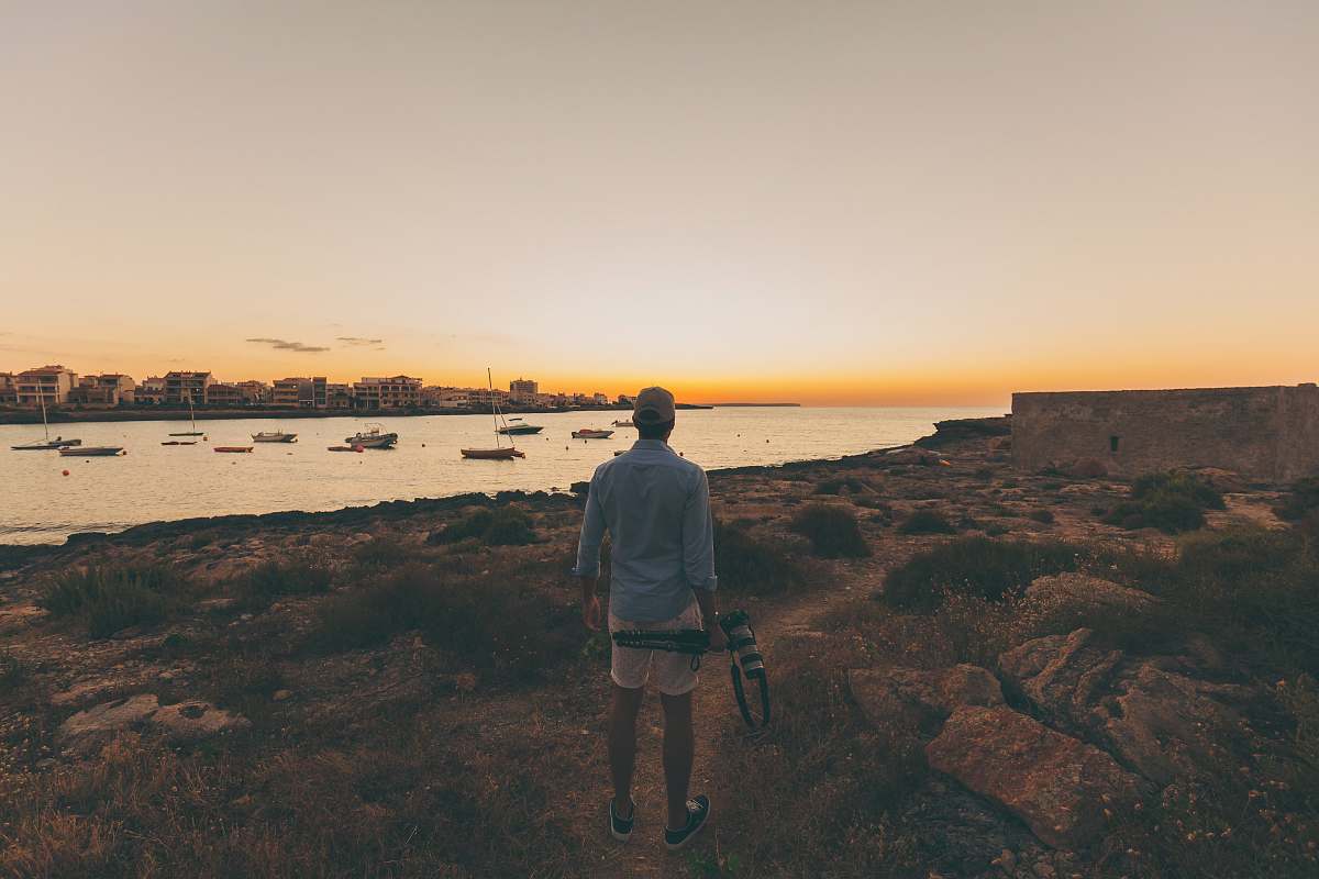 human person standing in open area overlooking body of water person