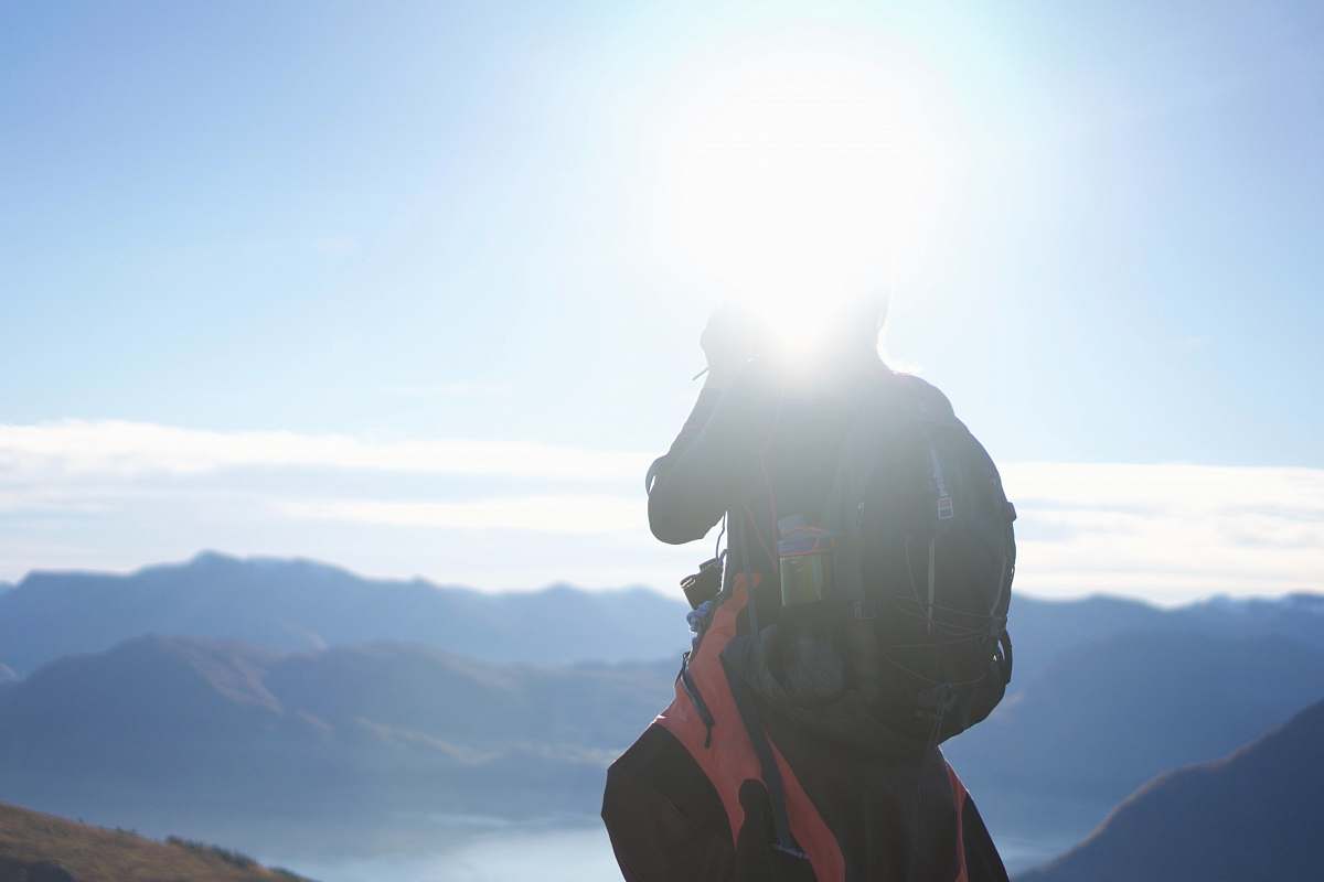 human person standing on cliff during daytime person