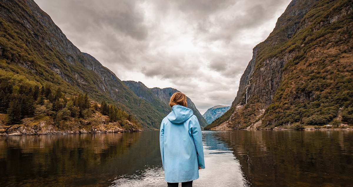 person person wearing blue hooded jacket facing mountain human