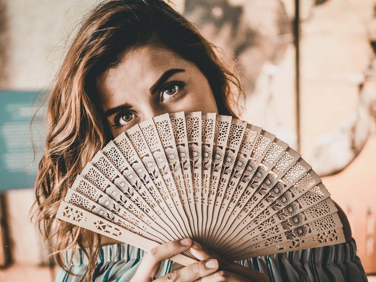 human photography of woman holding brown hand fan person