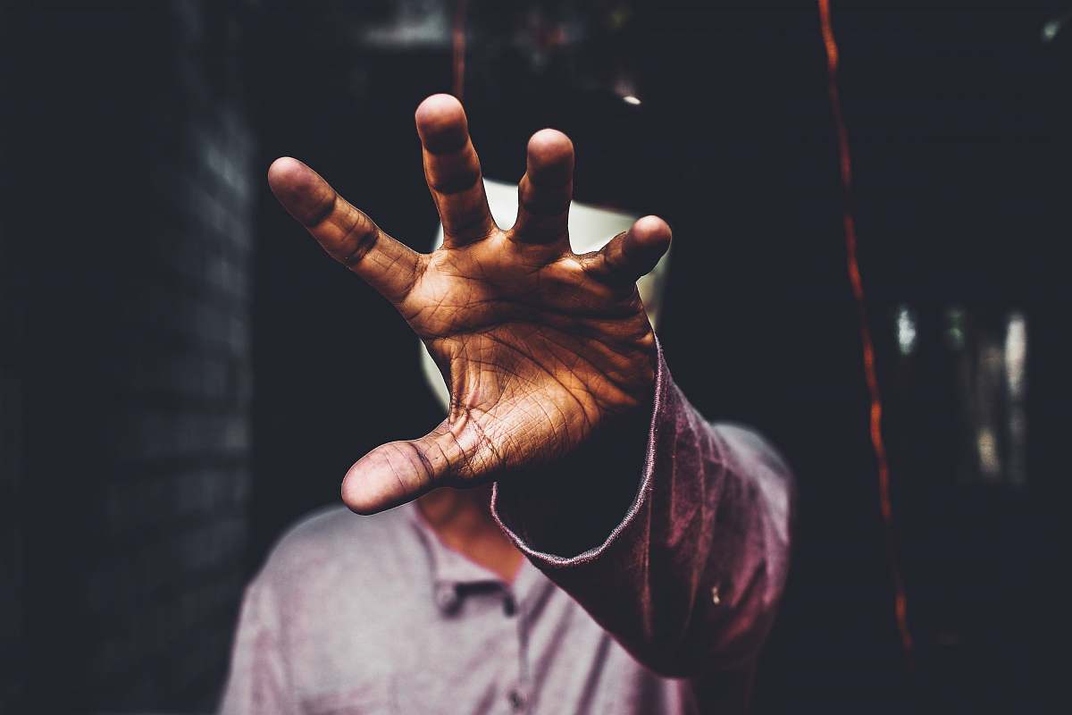 human selective focus photography of man raising his right hand during daytime person