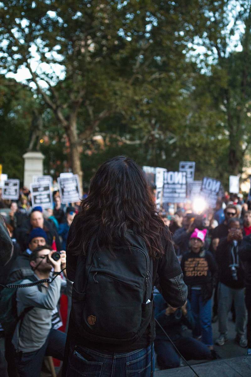 human selective-focus photography of man standing front of people at daytime crowd