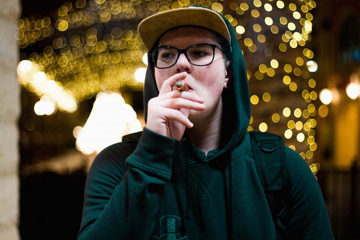 human smoking man wearing green pullover hoodie with bokeh background person