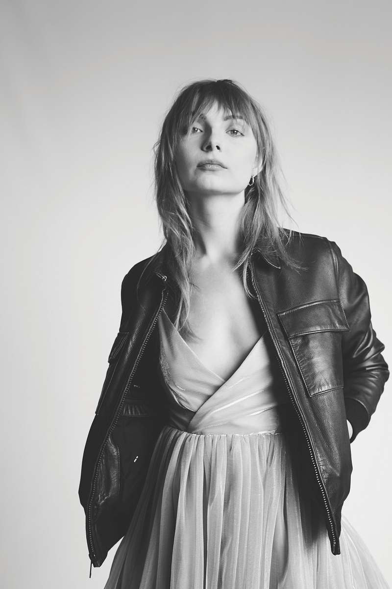 black-and-white standing woman with hands in jacket's pockets grey
