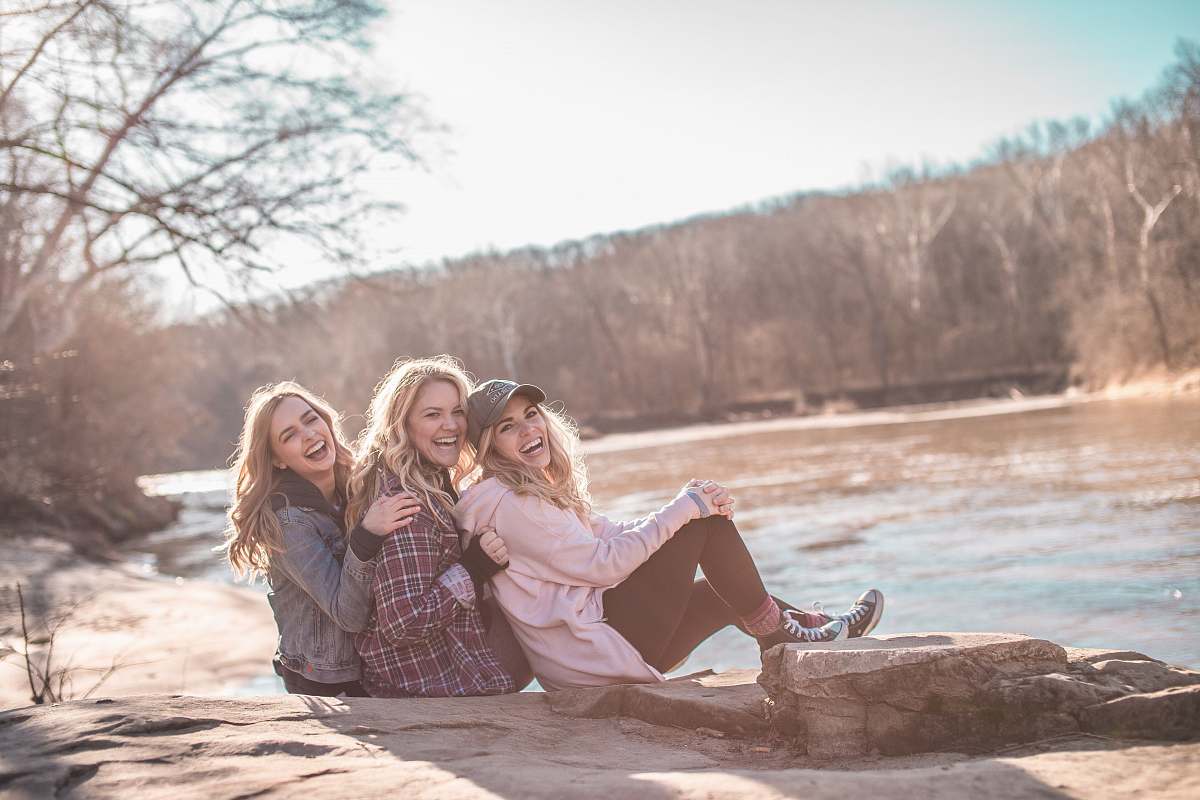 woman three women sitting on rock near body of water blonde