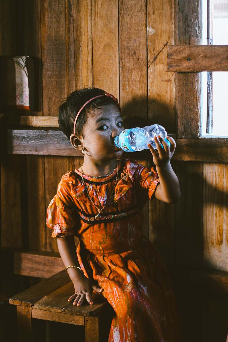 human toddler sitting on stool chair while drinking water person