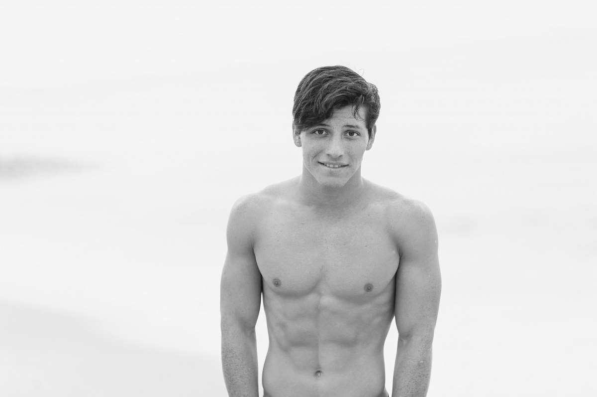 person topless man standing on seashore black-and-white
