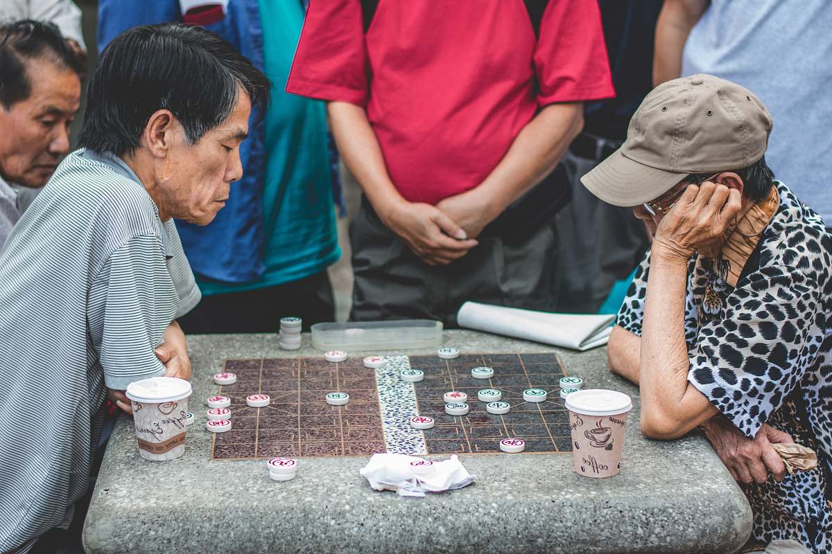 cup two men sitting beside table playing game game