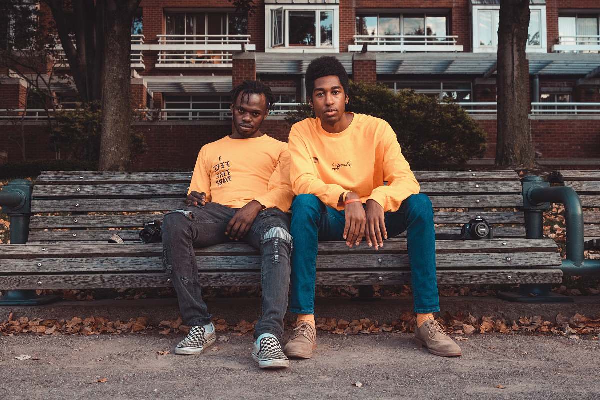 human two men's sitting on brown wooden bench chair person