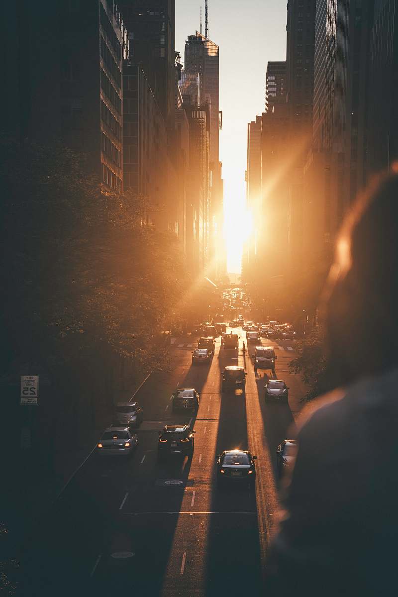 human vehicles passing between buildings during sunset person