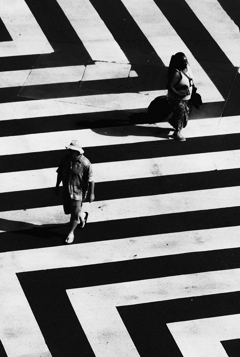black-and-white woman and man waling on white and black striped road road