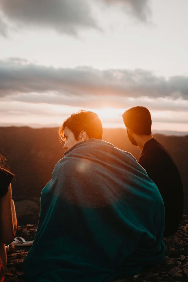 human woman covering green textile near man sitting during sunrise person