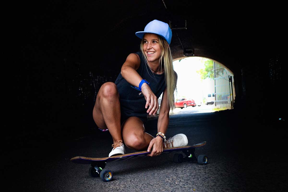 human woman crouching while riding on skateboard during daytime shallow focus photography person
