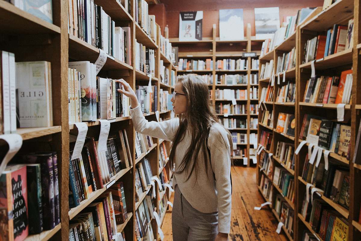 person woman holding book on bookshelves book