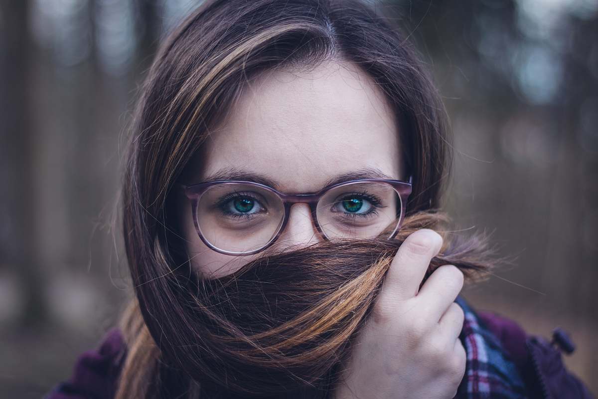 person woman holding her hair during daytime glasses