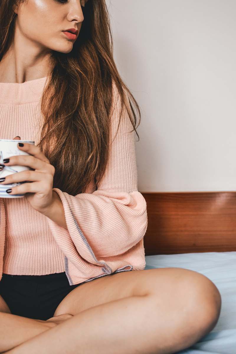 human woman holding mug sitting on bed person