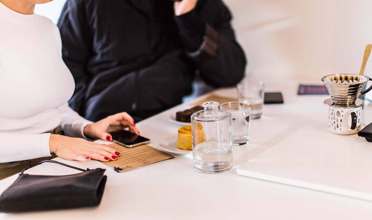 person woman holding smartphone beside clear drinking glass on table human