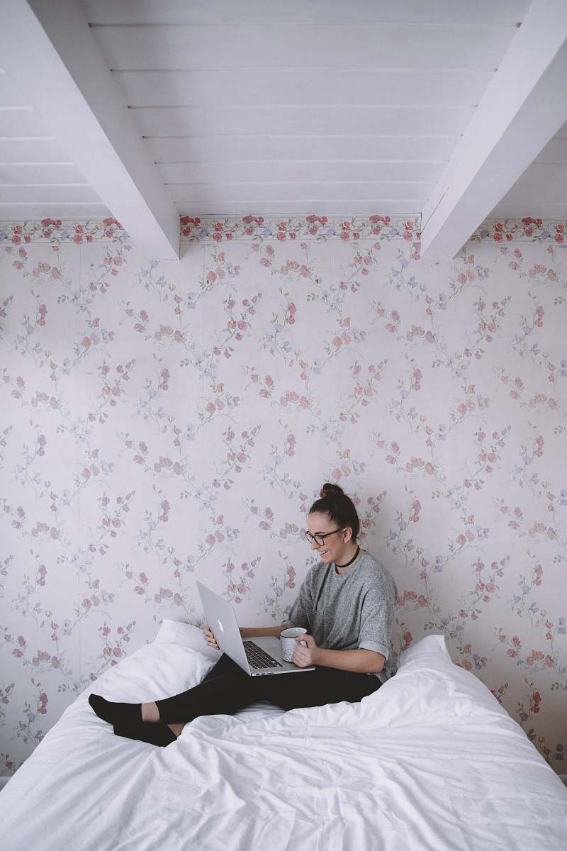human woman holding white ceramic cup while using laptop person