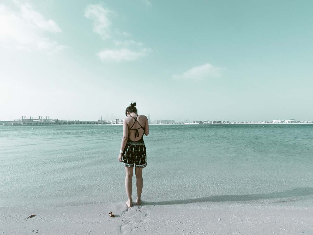 beach woman in black outfit standing on beach sand coast