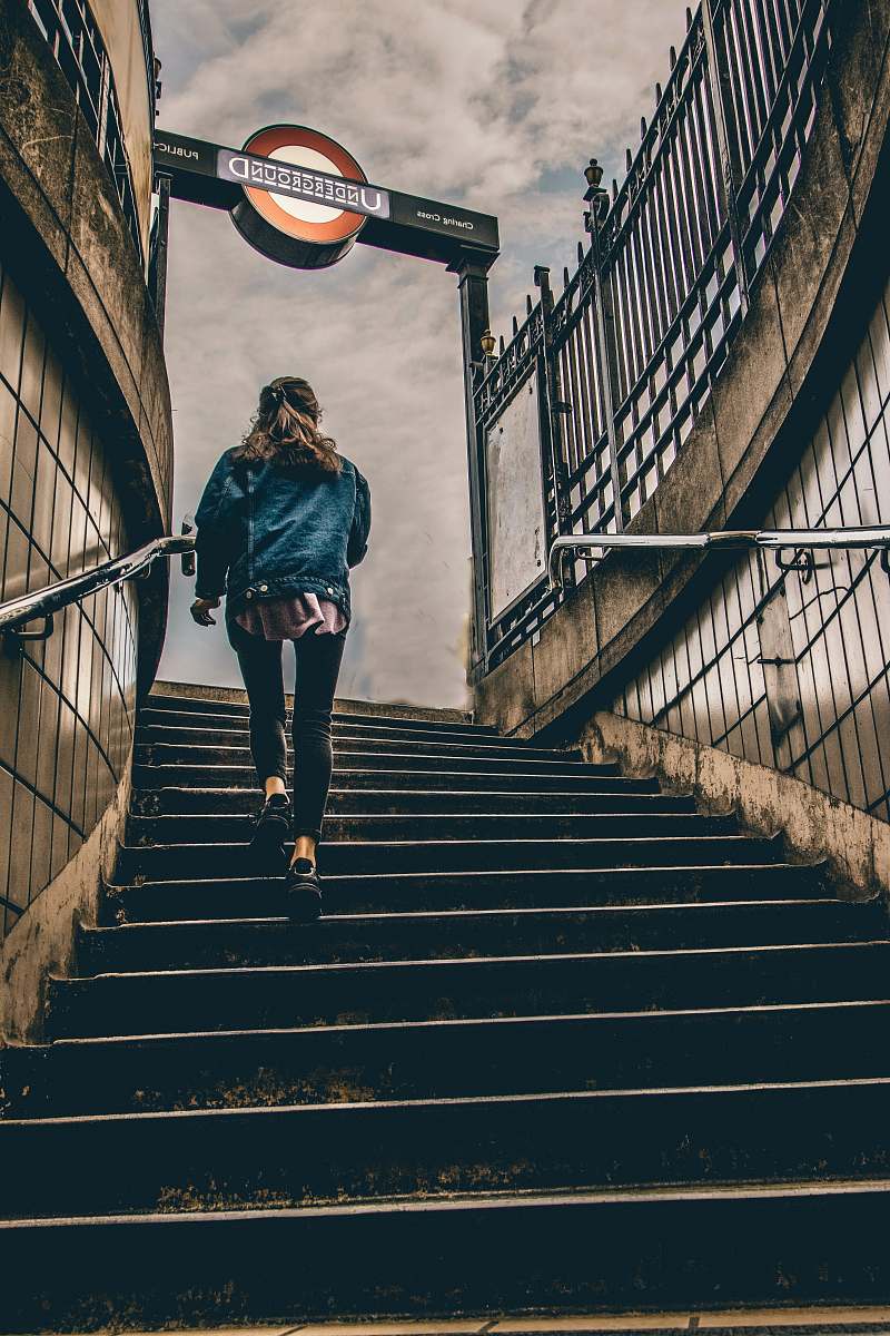 person woman in blue denim button-up jacket walking on concrete stairs during daytime london
