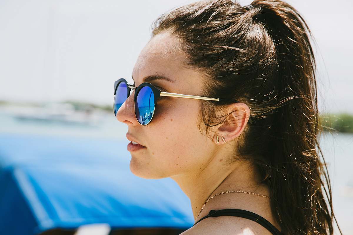 human woman in blue sunglasses in front of blue car during daytime shallow focus photography person
