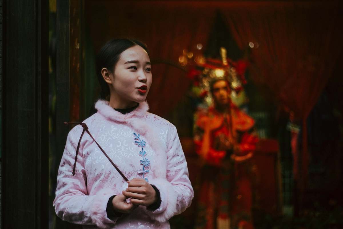 human woman in pink sweatshirt holding stick shallow focus photography temple