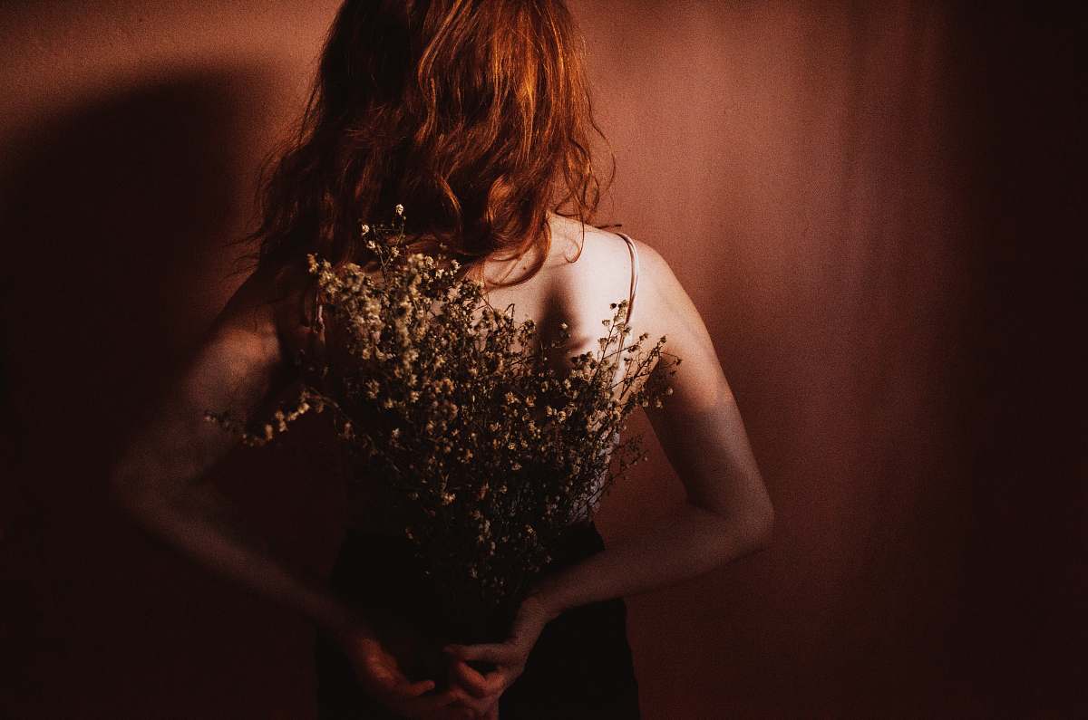 person woman ion dress standing in front of wall flowers