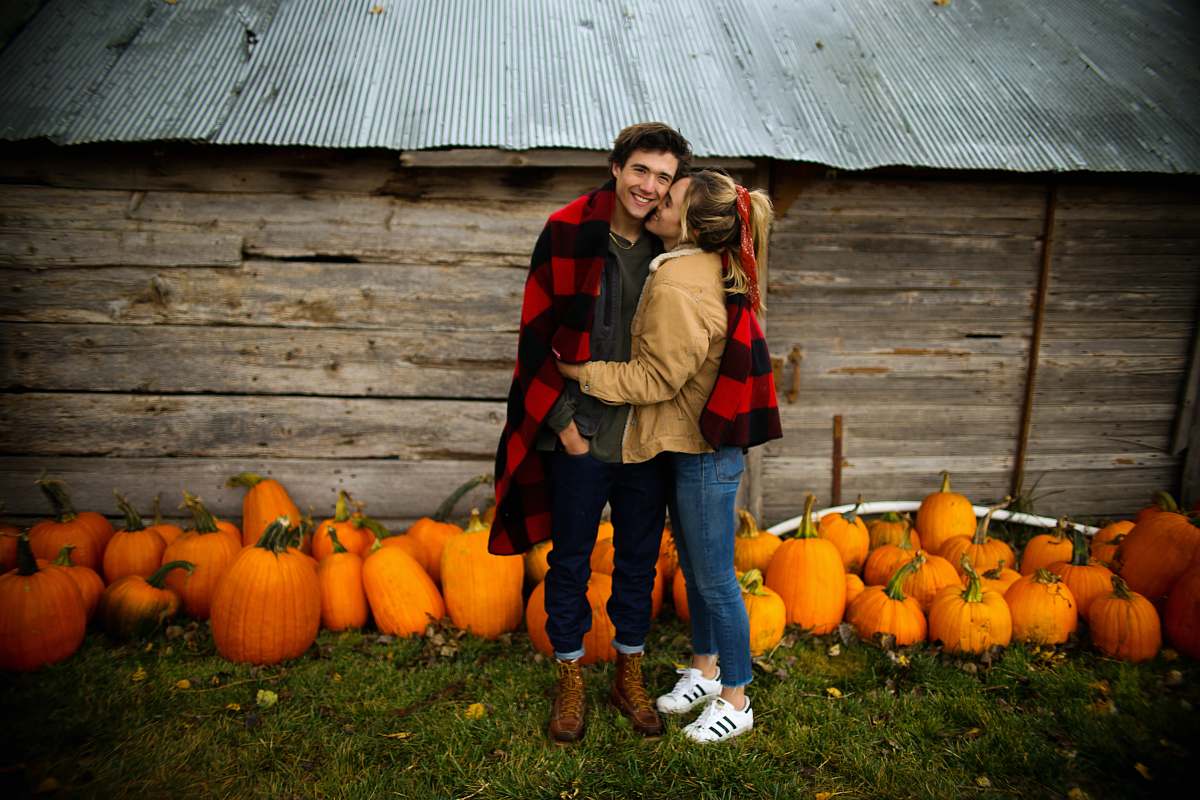human woman kissing man near pumpkins person